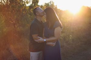 A tender embrace between a couple during sunset in a rustic outdoor setting.