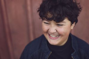A joyful candid portrait against a rustic brown background.