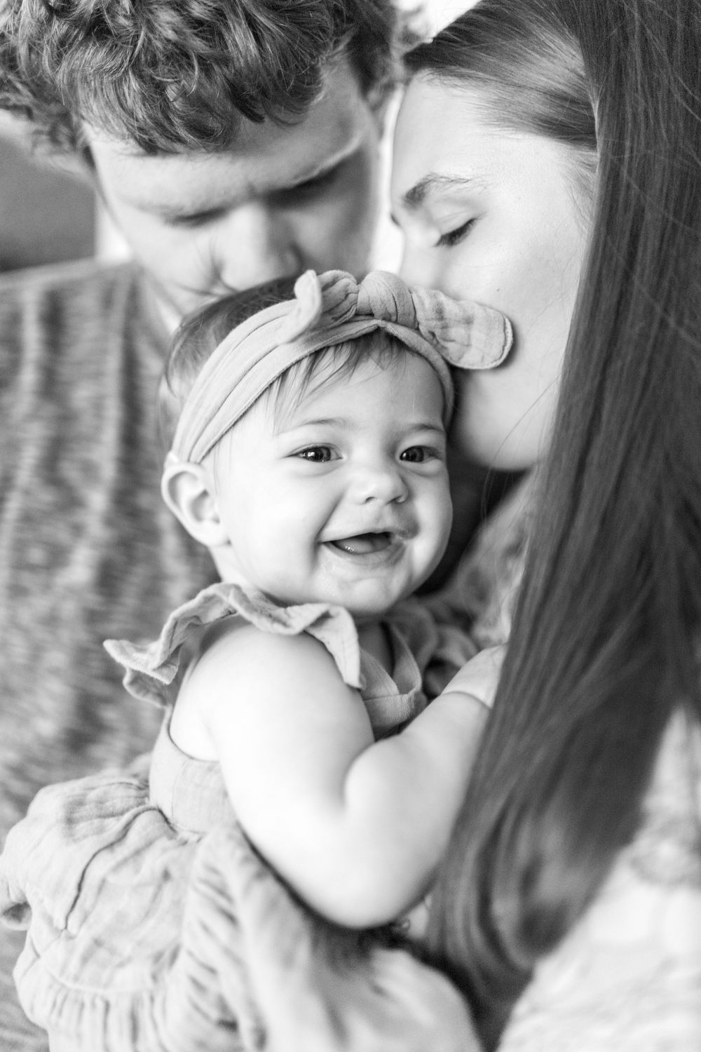 A sweet black and white portrait of tender family moment with a smiling baby.