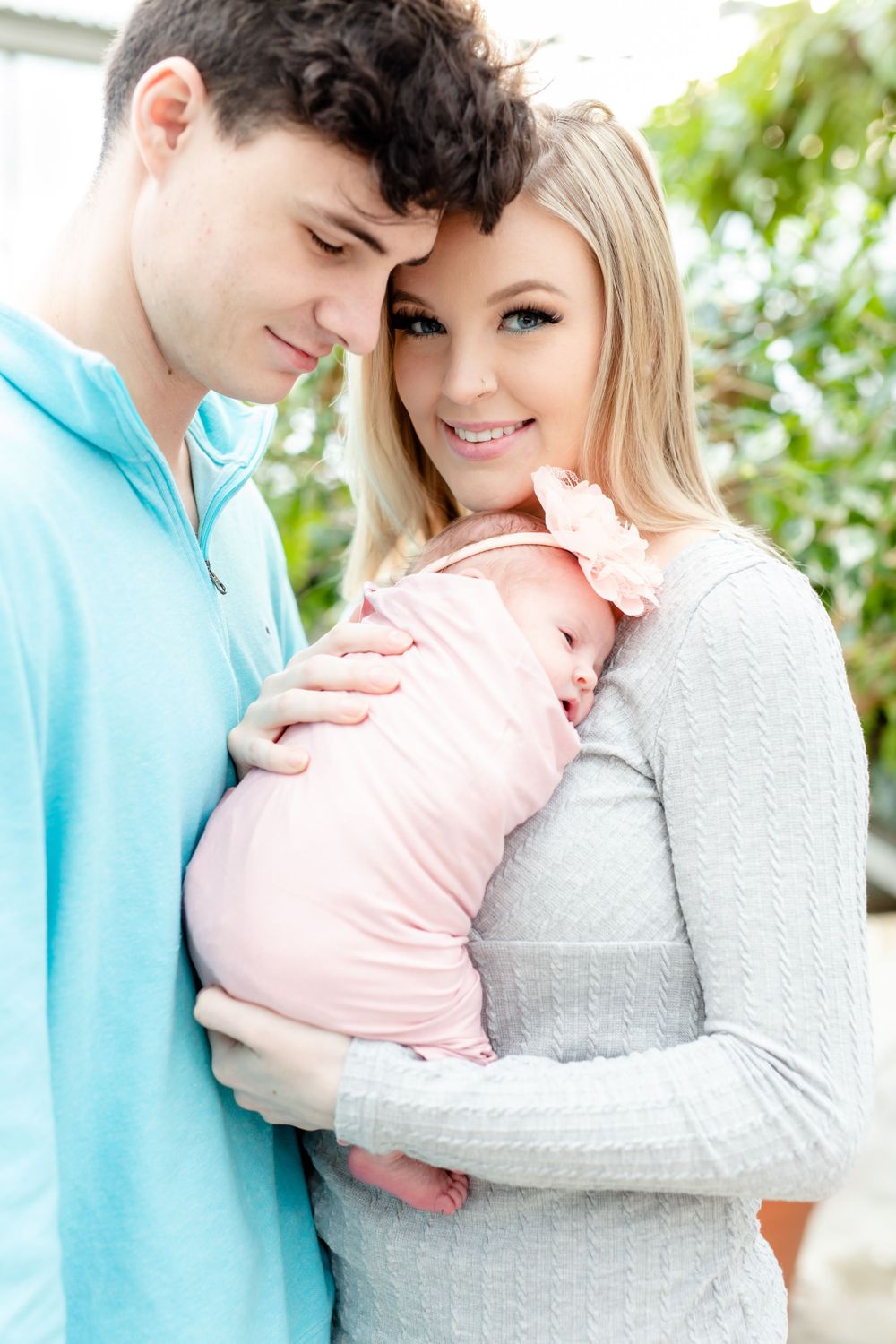 Tender family moment as couple holds their newborn wrapped in pink.