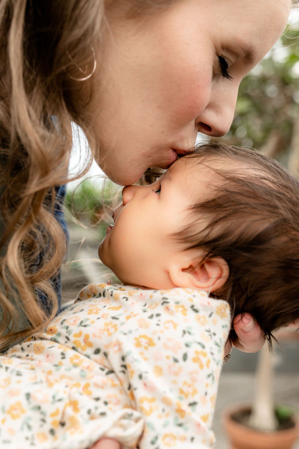 A tender moment captured between a parent and baby in floral clothing.