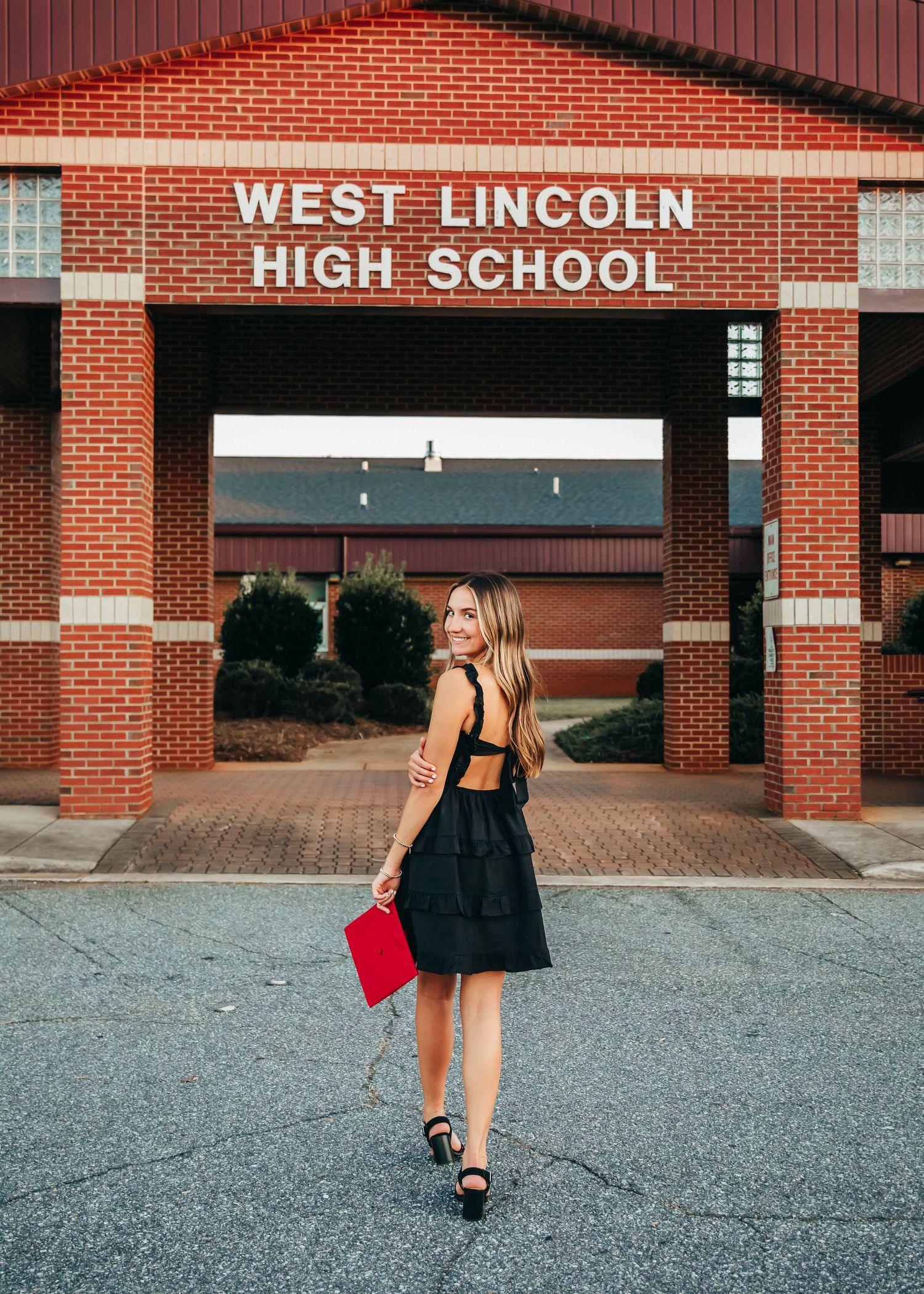 Senior photos taken outside West Lincoln High School with graduate in black dress.