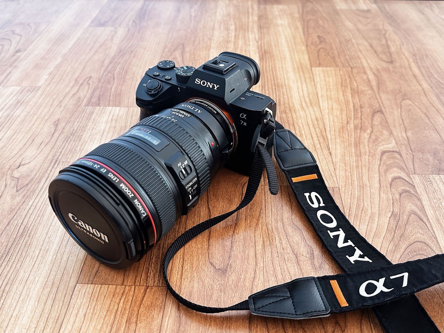 Sony DSLR camera body and lens arranged on a wooden surface.