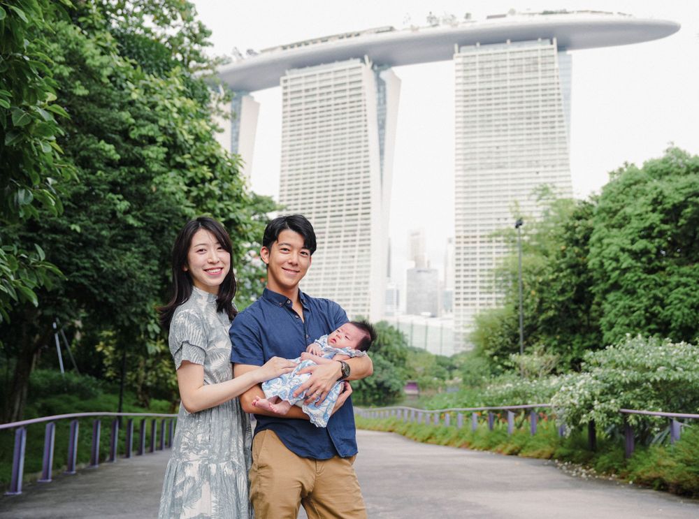 Family with baby outdoors at Gardens by the Bay with Marina Bay Sands hotel towering in background in Singapore.