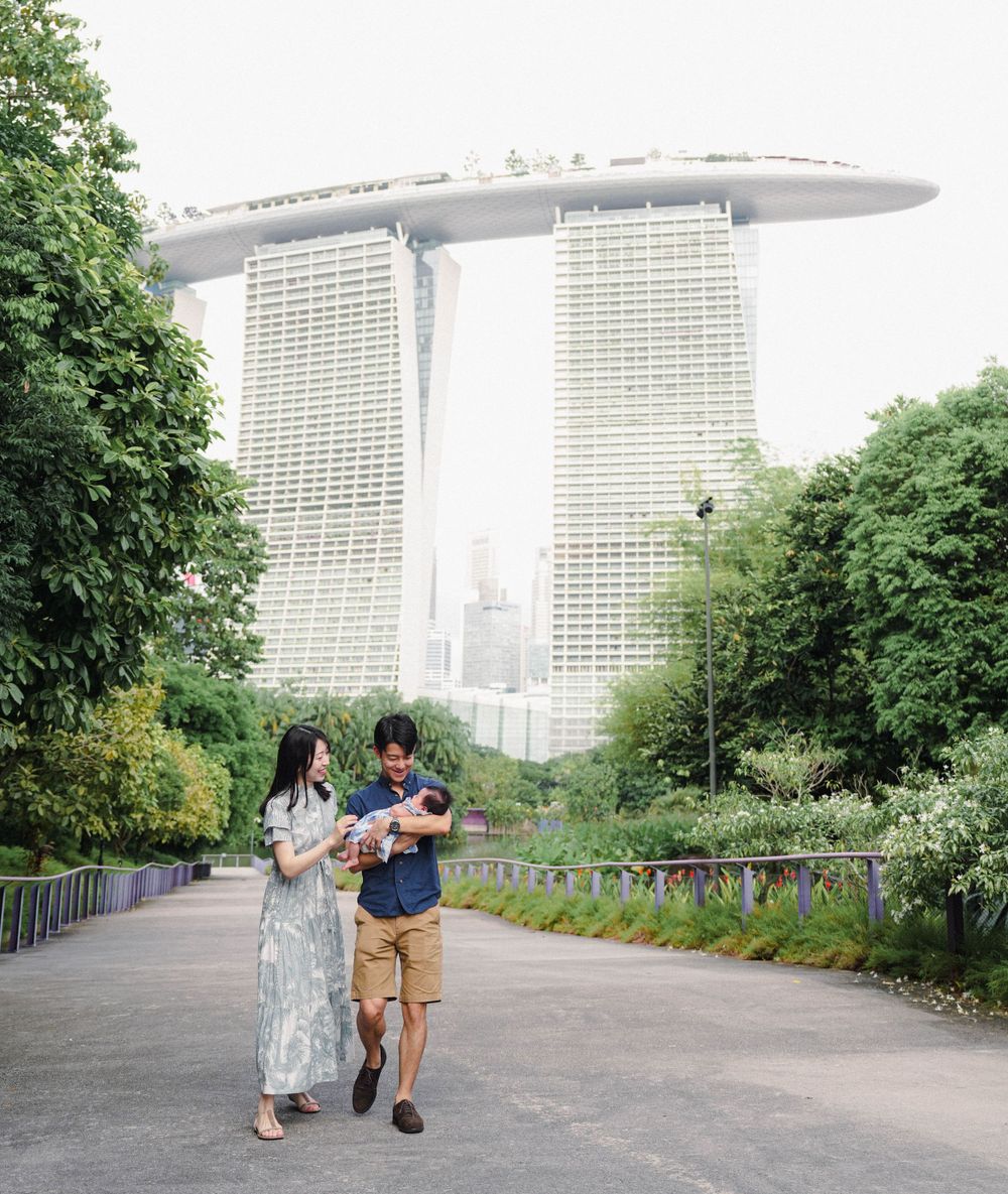 Two people walk along a pathway at Gardens by the Bay with Marina Bay Sands hotel visible in the background in Singapore.