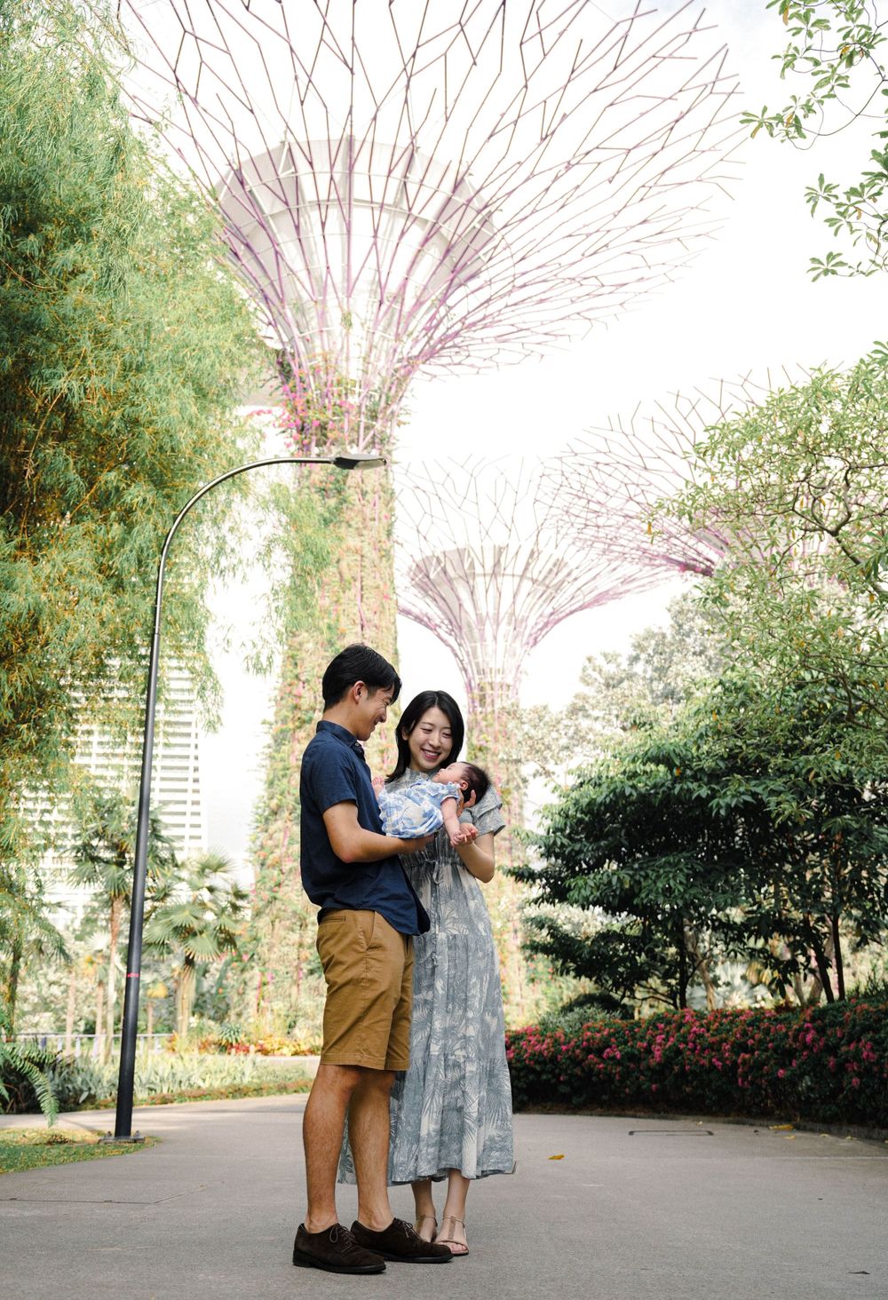 A couple stands together on a pathway at Gardens by the Bay in Singapore with the Supertree Grove structures visible above.