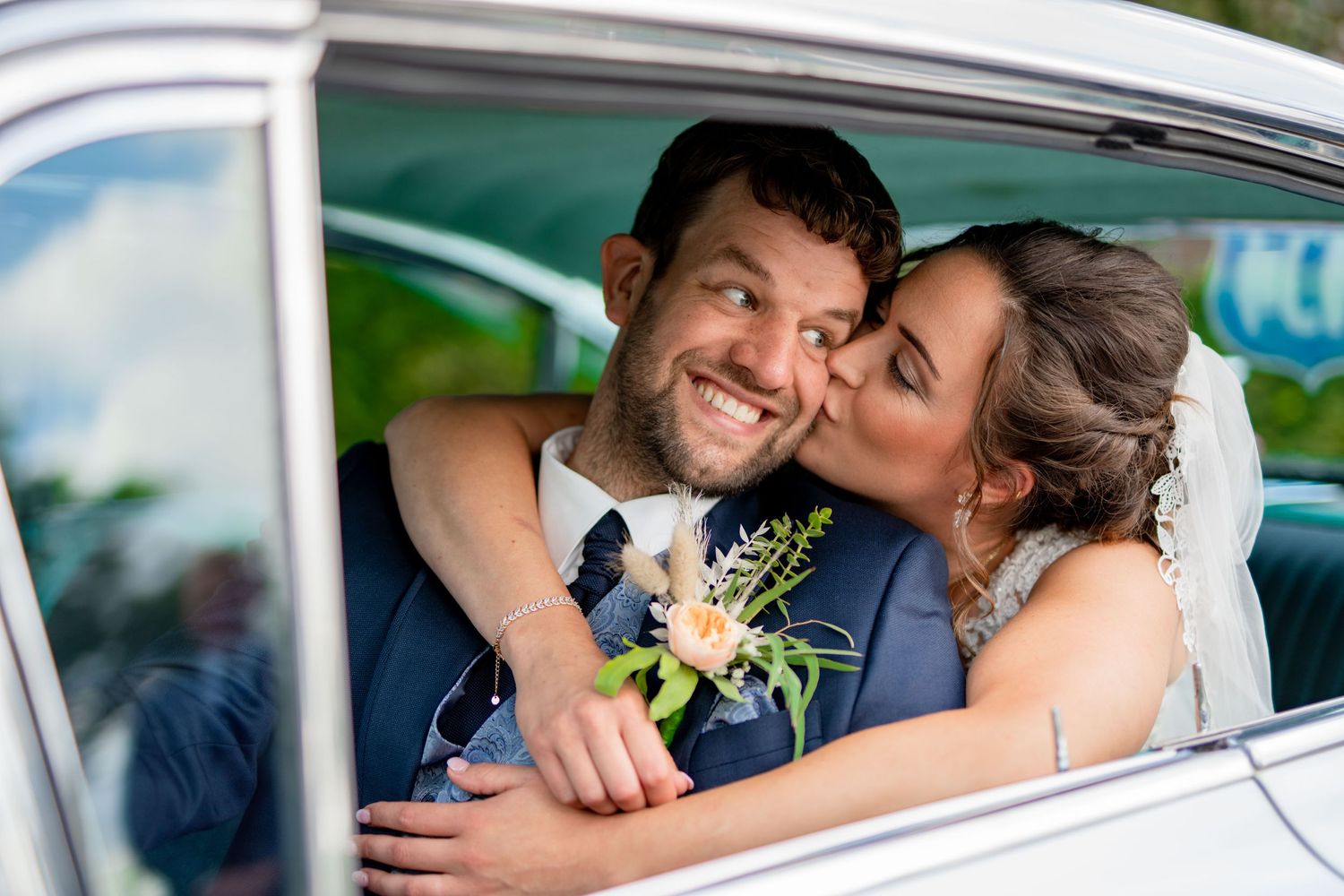 Newlywed couple sharing a joyful moment together in their wedding car on their special day.
