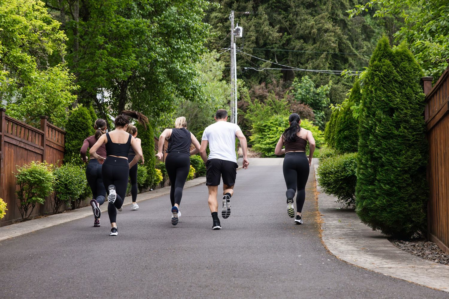 Group of runners exercising together on a tree-lined residential street during an outdoor workout session.