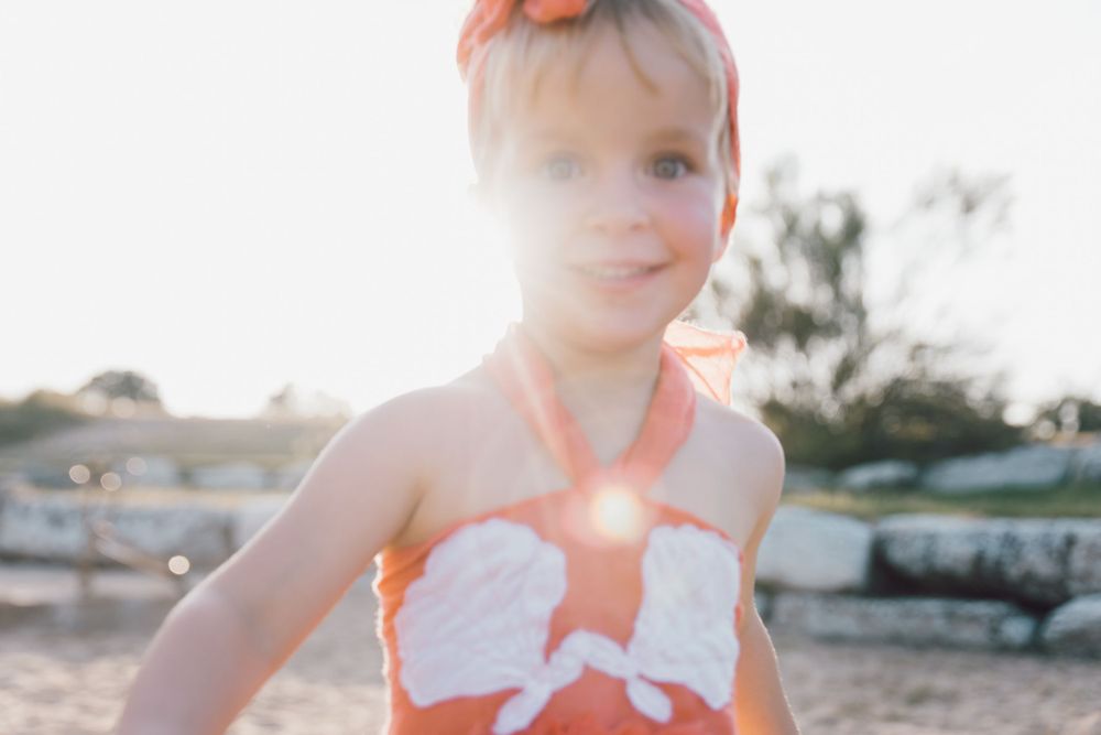 Soft sunlight glows through a dreamy summer scene with an orange and white floral outfit.