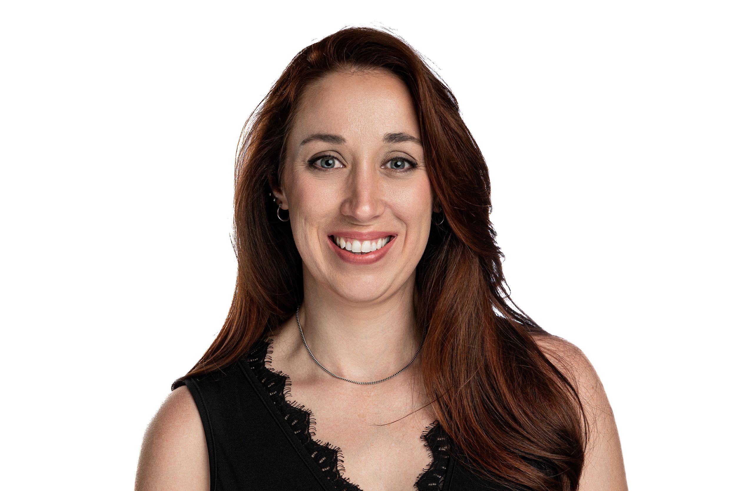 Studio portrait with black lace top against white background showing bright smile.
