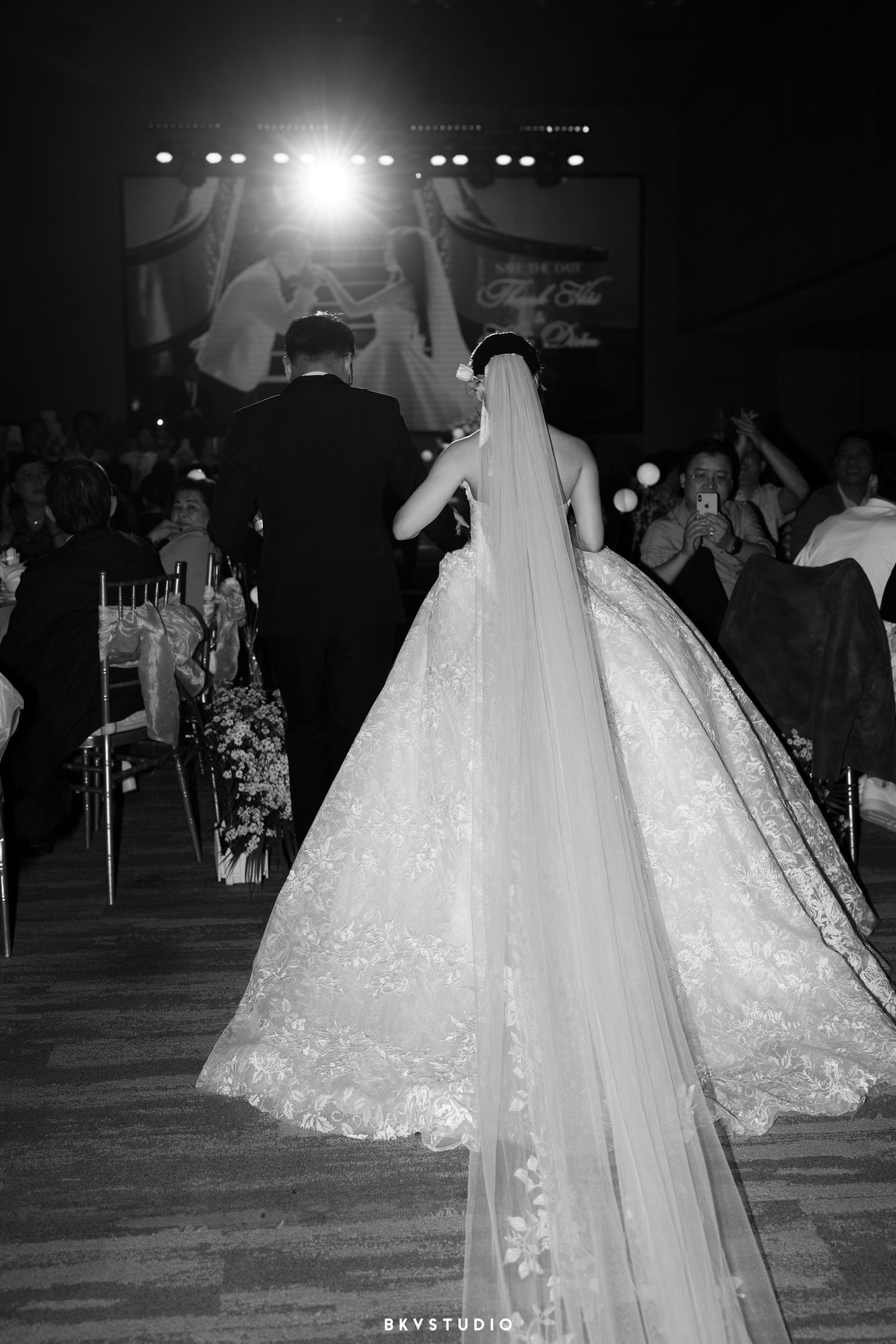 A couple celebrates at their wedding reception, with the bride wearing a stunning lace ballgown and long veil on the dancefloor.