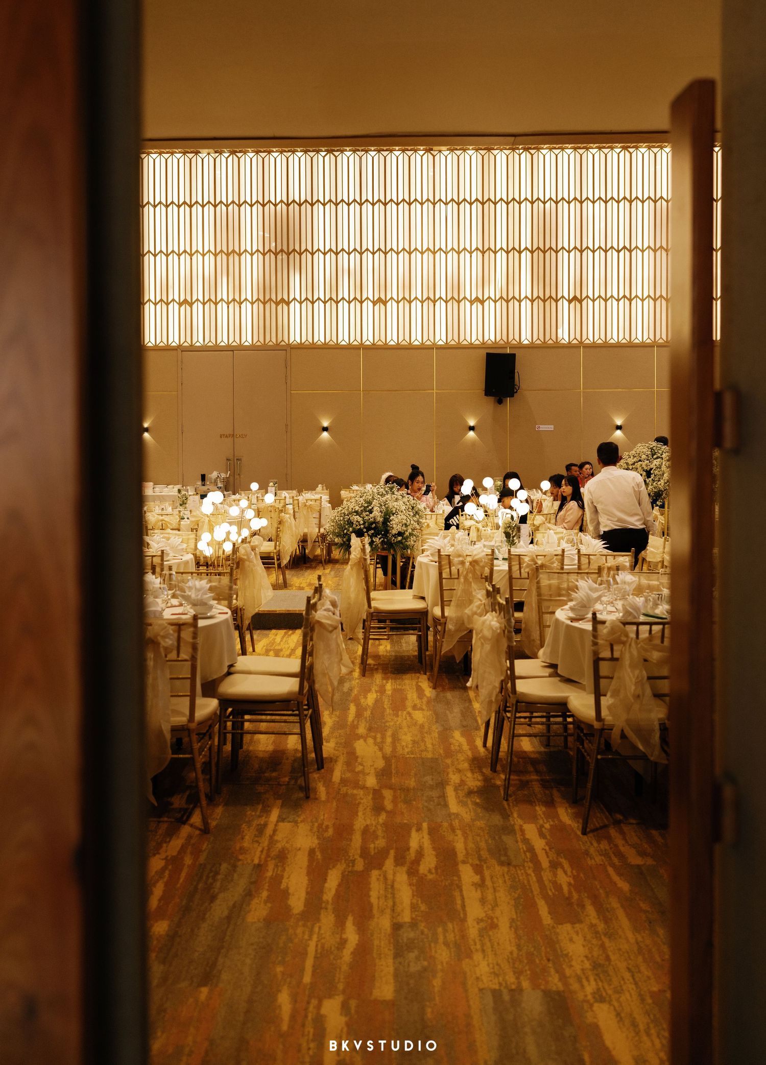 Elegant wedding reception venue with warm lighting, hardwood floors and tables decorated with glowing centerpieces.