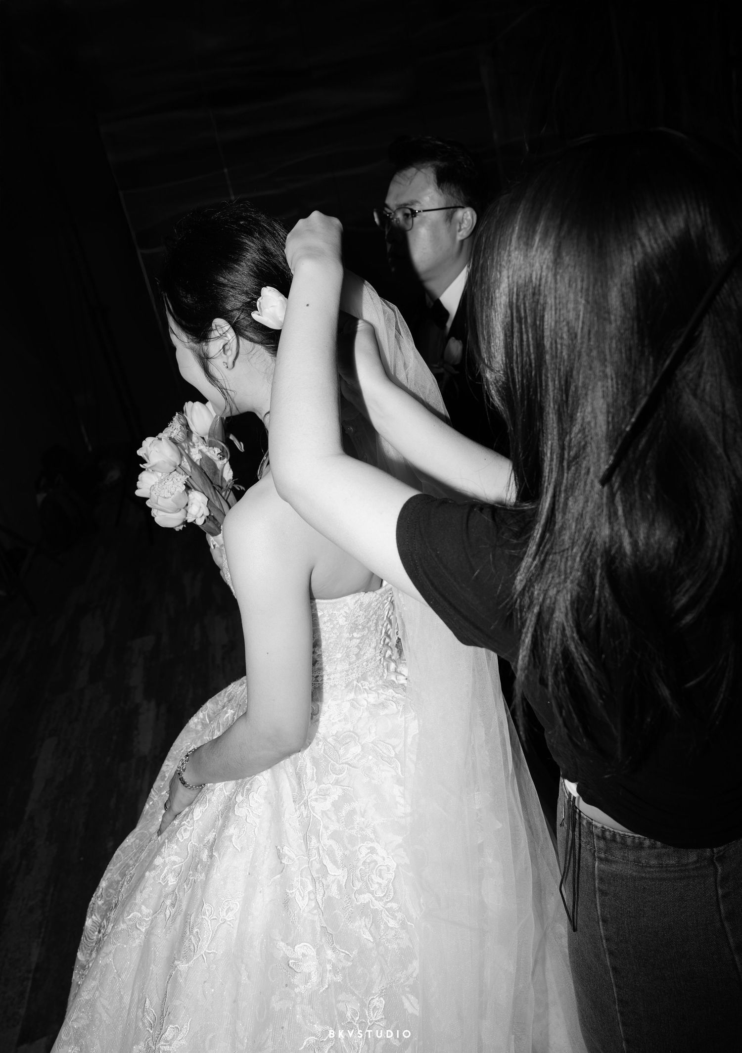 A black and white photograph of a wedding reception dance moment where couples sway together in the darkness.