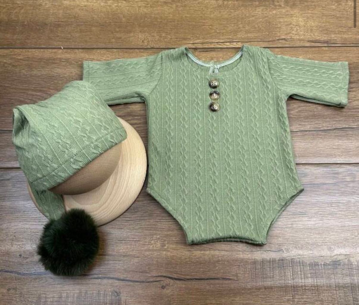 Sage green cable knit baby romper and matching hat with pom pom detail.