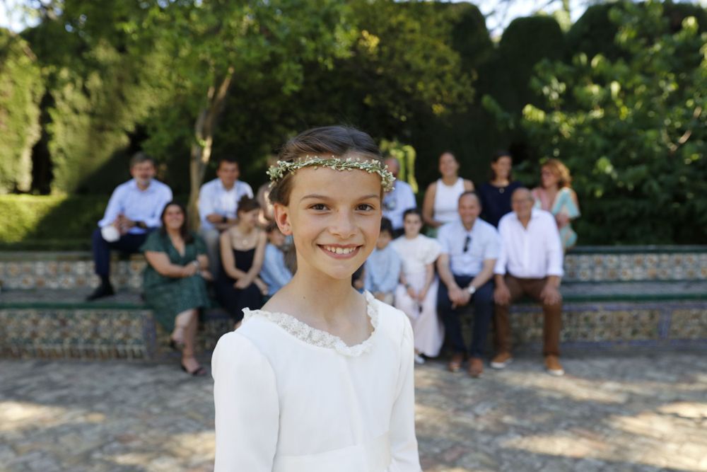 White-clad group gathers outdoors on stone steps with greenery in background on a sunny day.