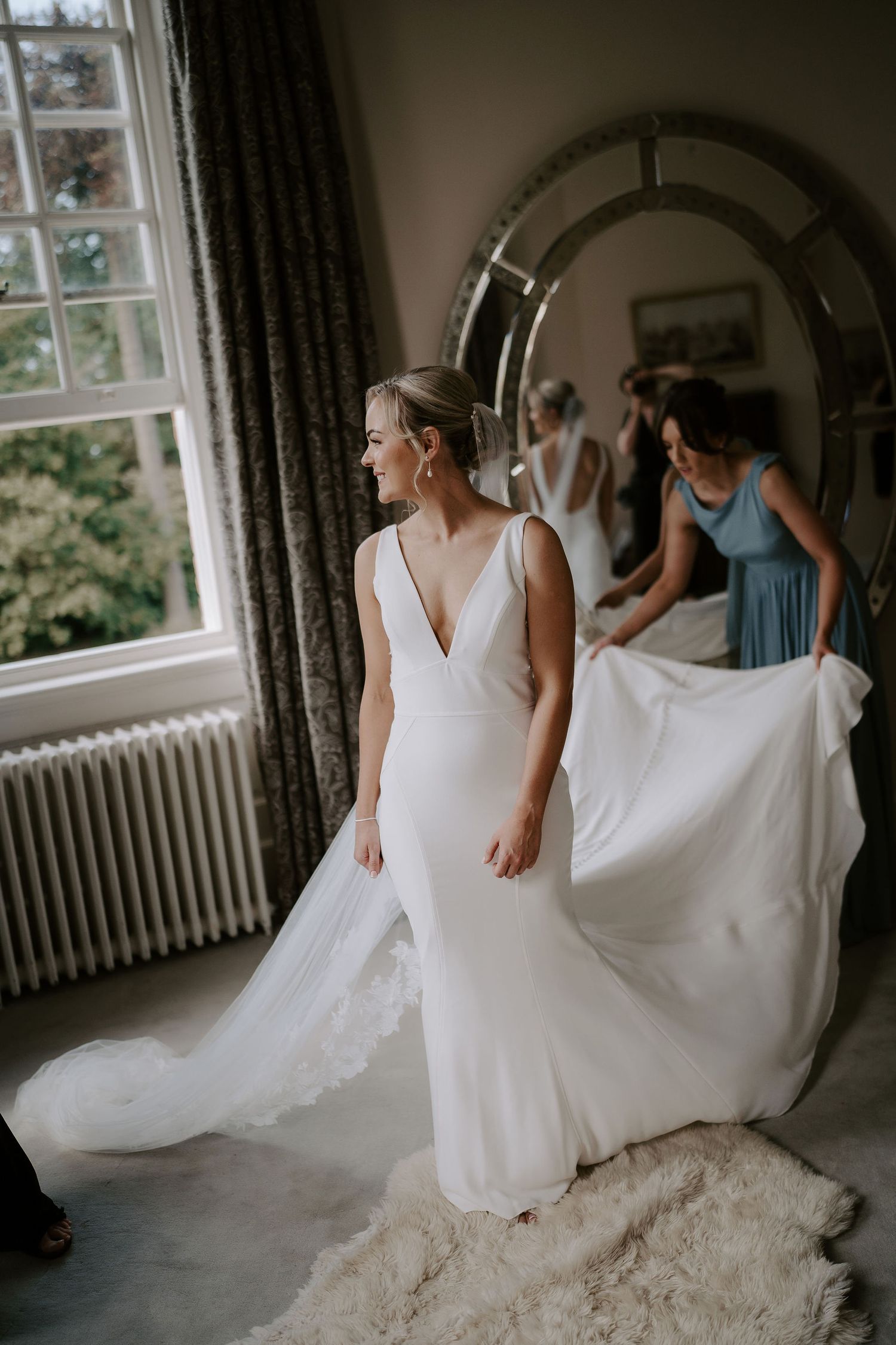 bridesmaid arranging brides dress at Iscoyd park