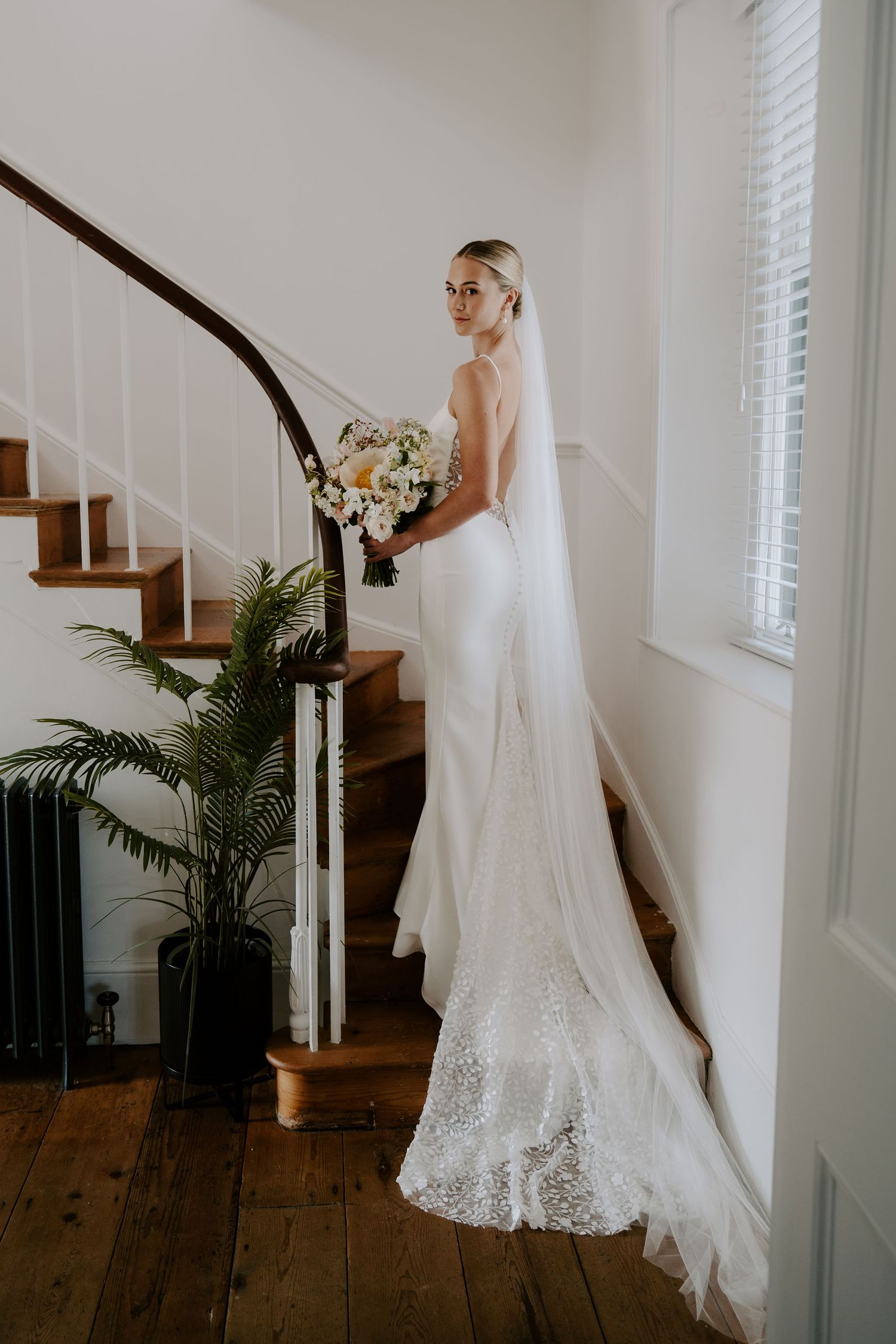 Tunnels Beach Wedding Venue in North Devon, Bride with bouquet on stairs