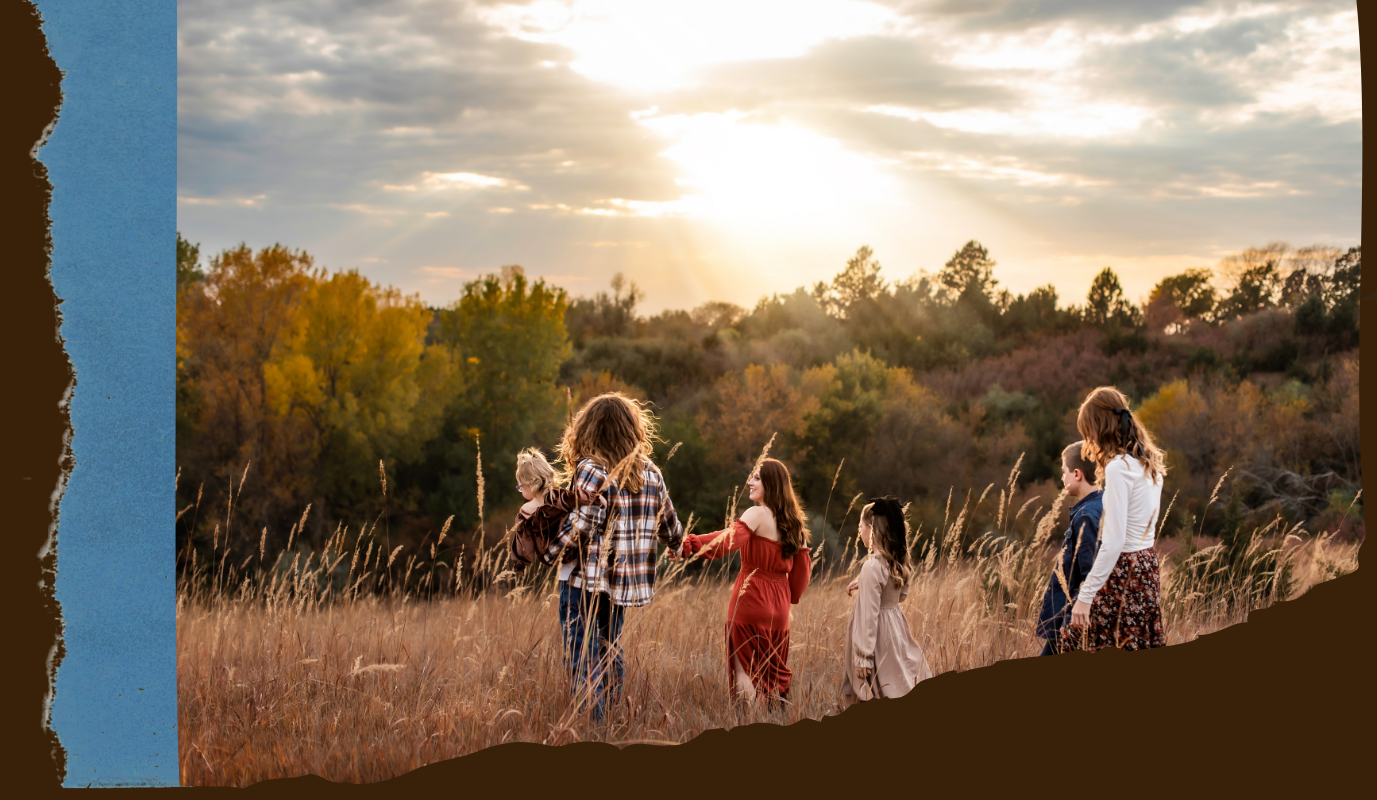 Golden hour sunlight illuminates silhouettes of people walking through a serene autumn field with tall grass.