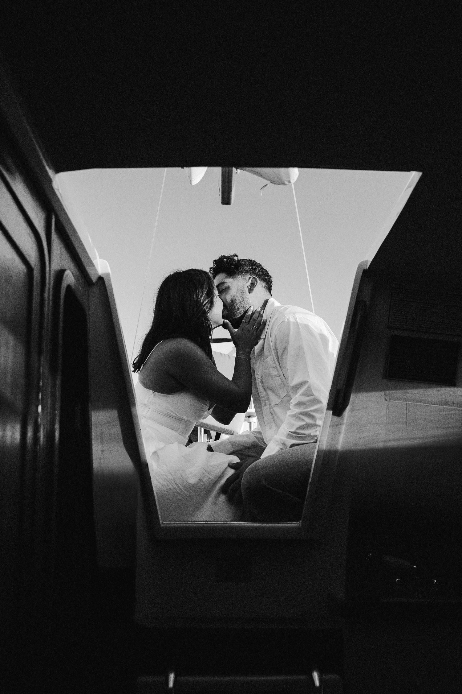 Black and white romantic silhouette of a couple sharing an intimate moment on a boat.