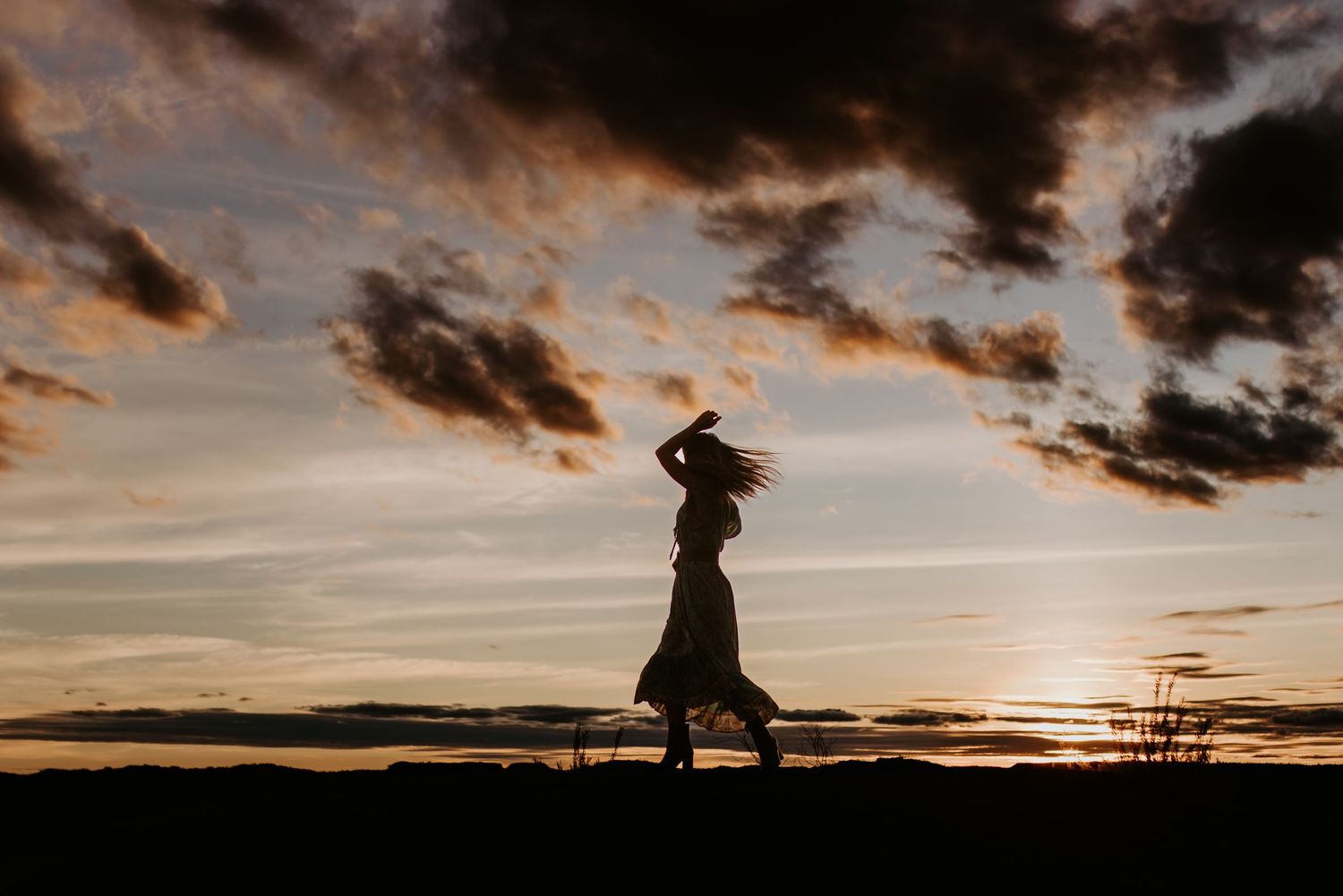 silhouette of woman dancing with the sunset behind her