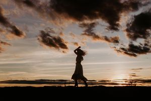 silhouette of woman dancing with the sunset behind her