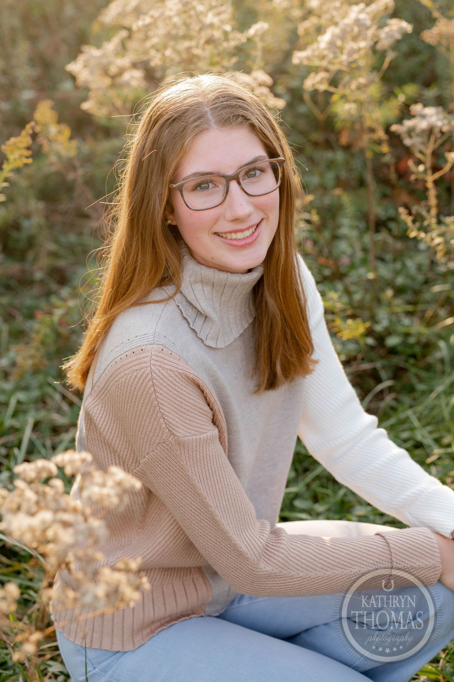 Autumn portrait featuring someone in glasses and a two-toned turtleneck sweater among dried plants.