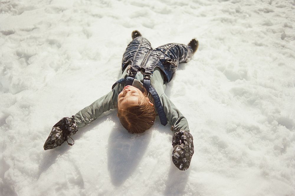 Someone making a snow angel while lying in fresh powder on a winter day.
