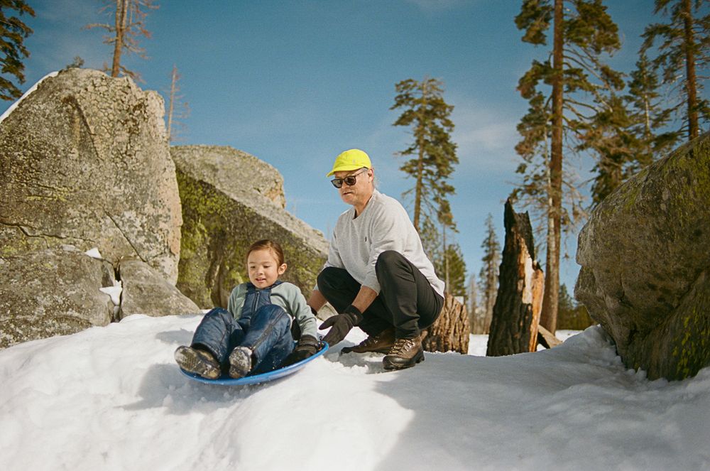 Winter sledding scene with people enjoying the snowy terrain among large boulders.