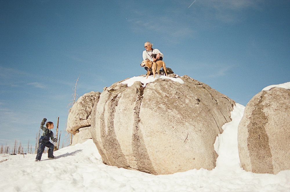 People playing in a snowy landscape with large granite boulders.