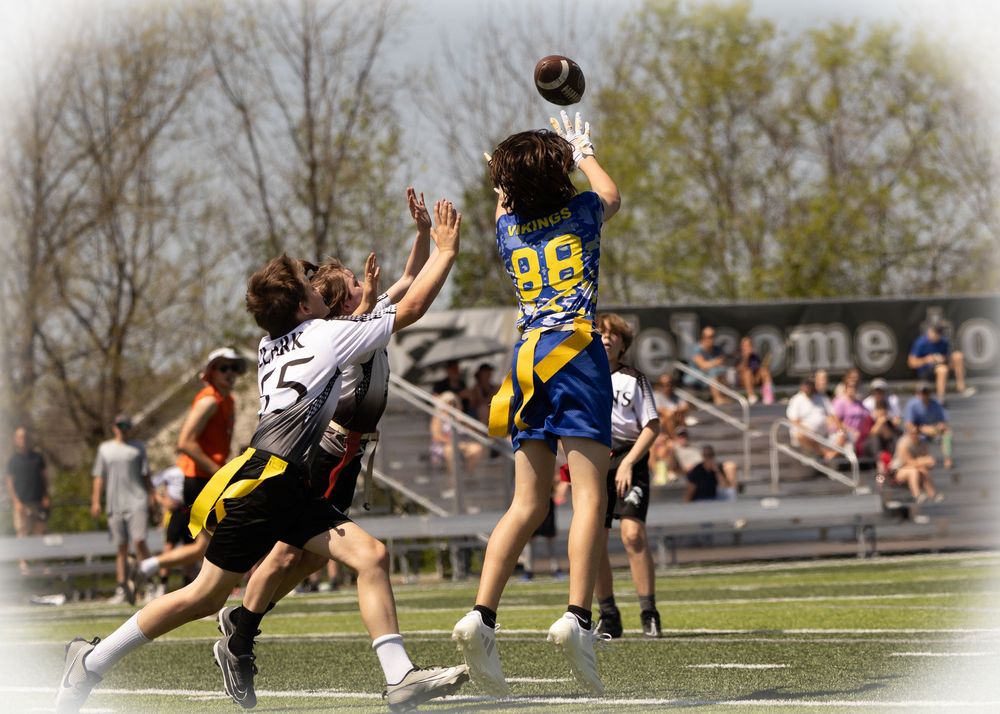 Ultimate frisbee players leap high to compete for a flying disc during an intense outdoor game on a sports field.