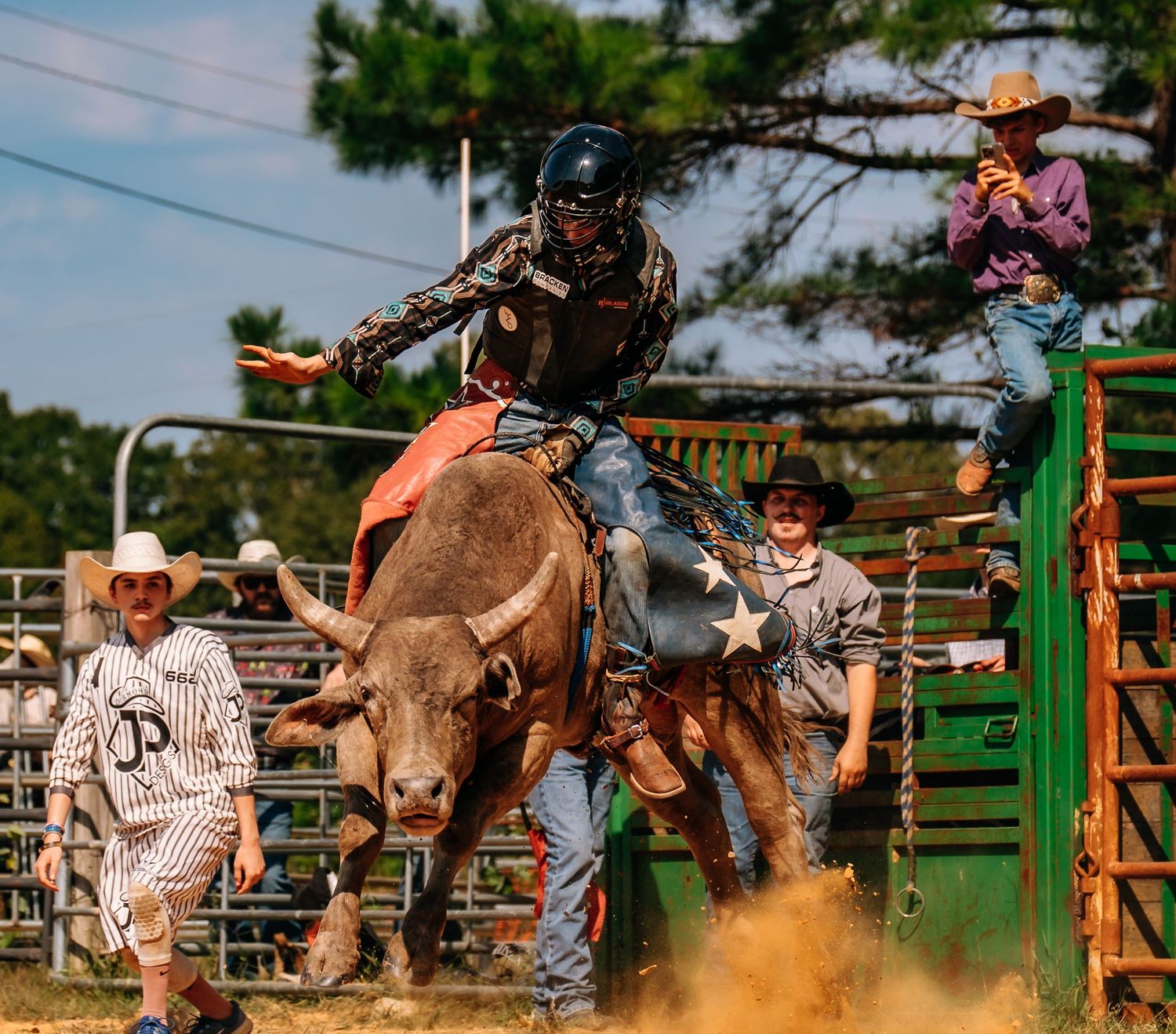 Action shot of bull rider during intense rodeo competition with spotters nearby.
