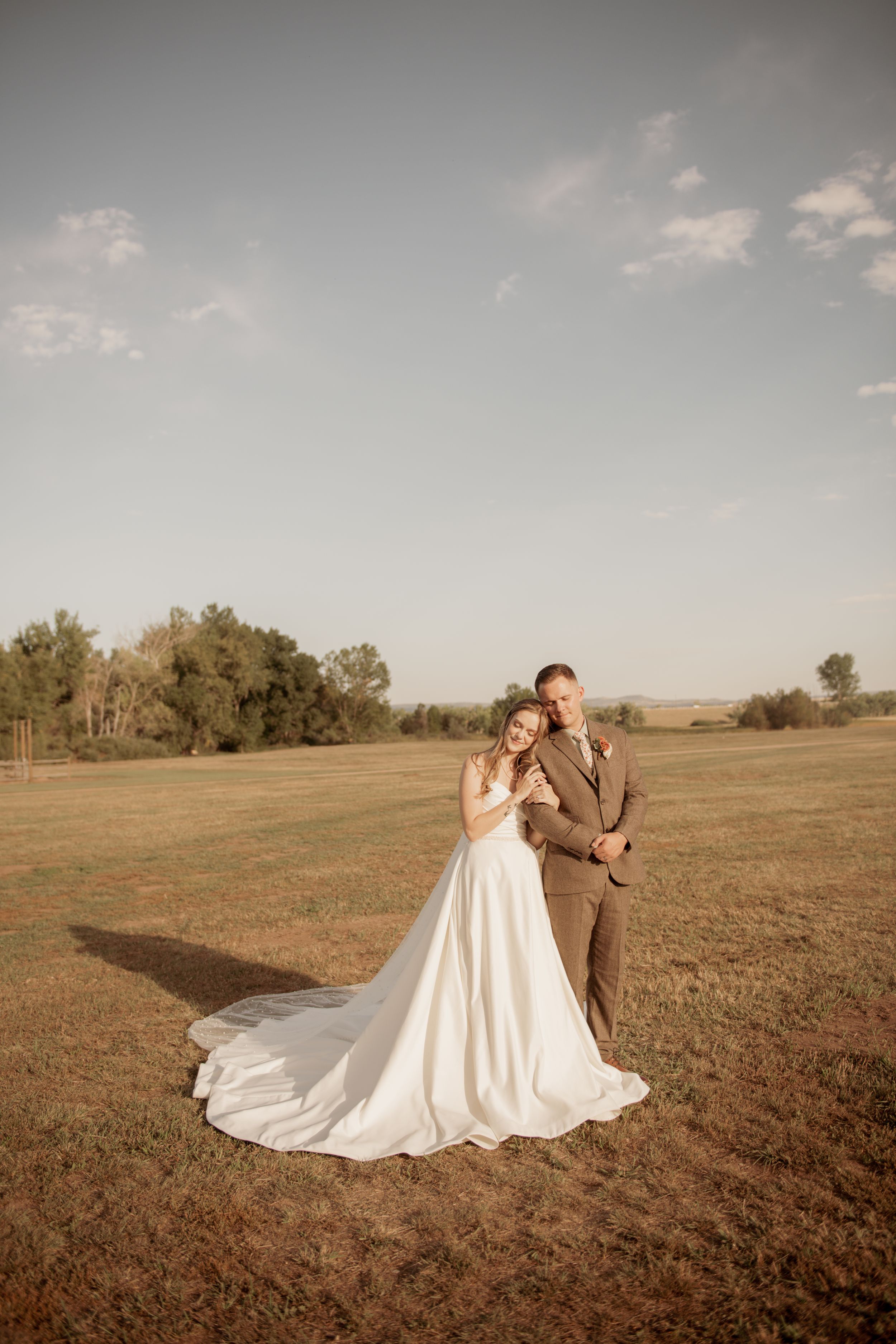 A romantic outdoor wedding photo session showing silhouettes of a couple in a rustic field at golden hour.