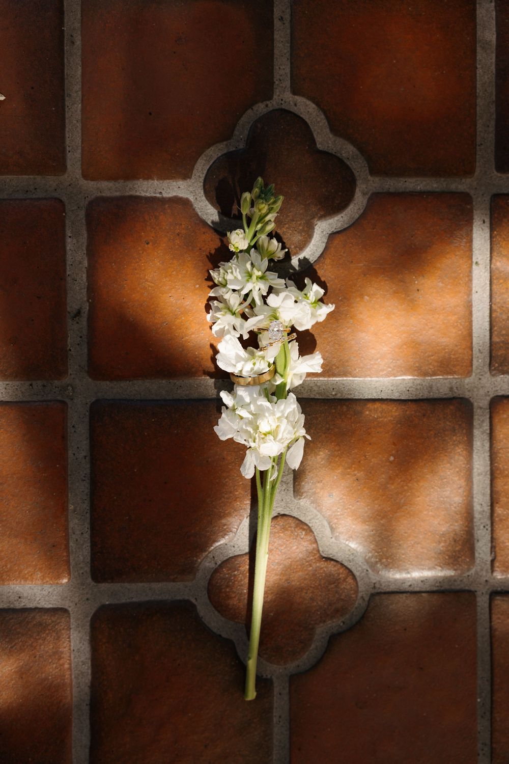 White floral boutonnieres displayed against a rustic brick wall with dramatic lighting.