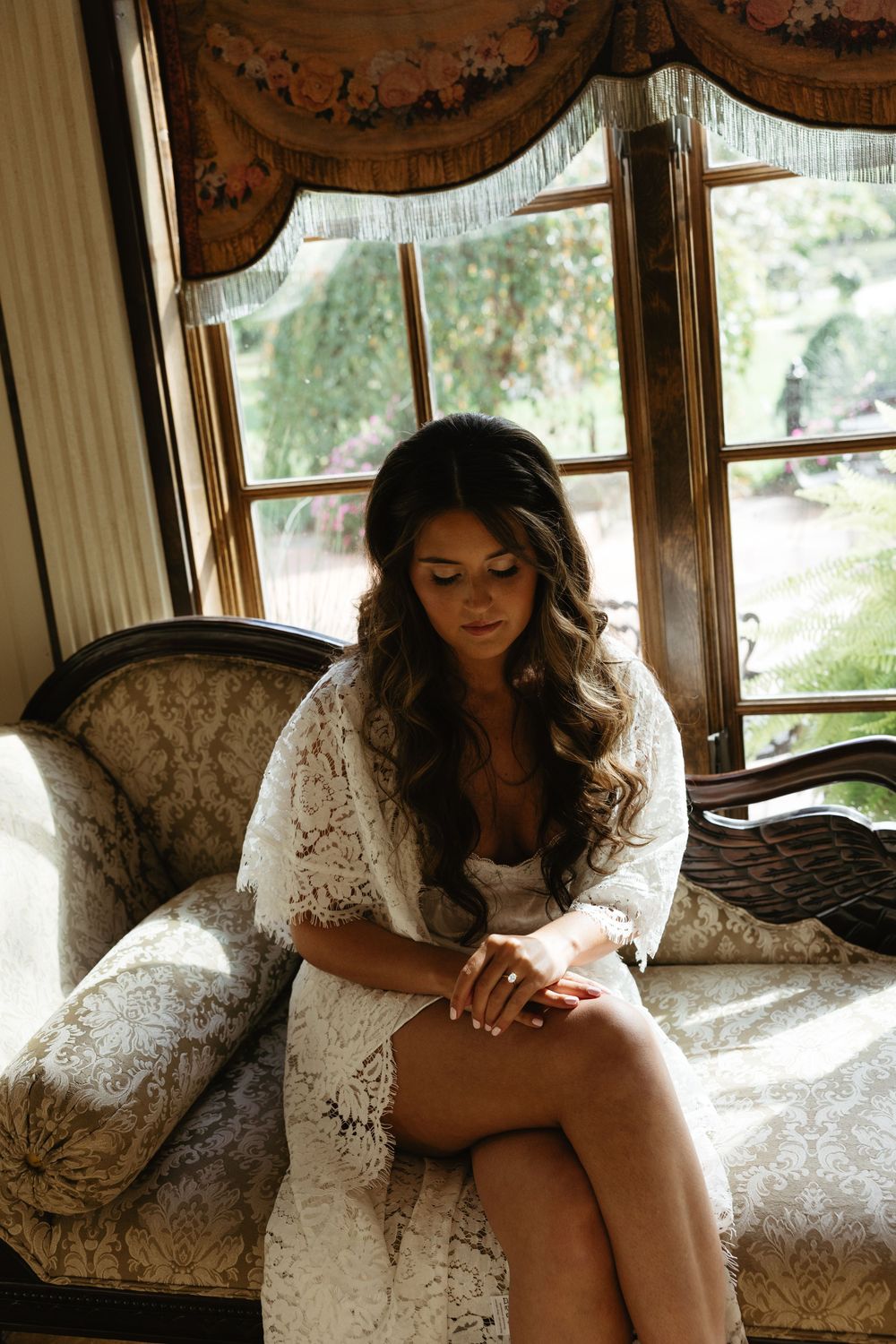 A series of artistic boudoir photos showing someone in white lace lounging on an antique chaise by a window.