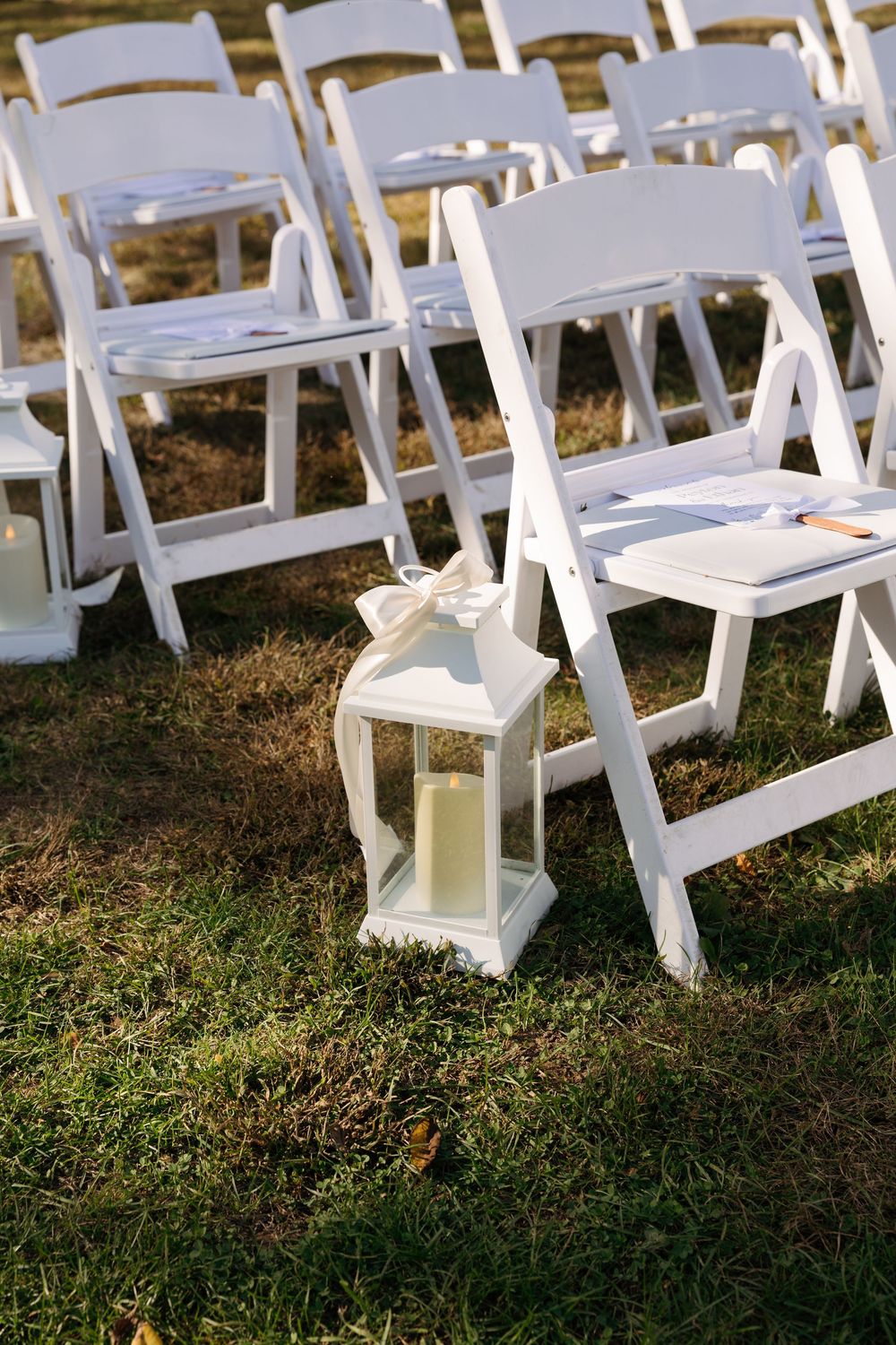 White folding chairs set up on grass for an outdoor wedding ceremony.