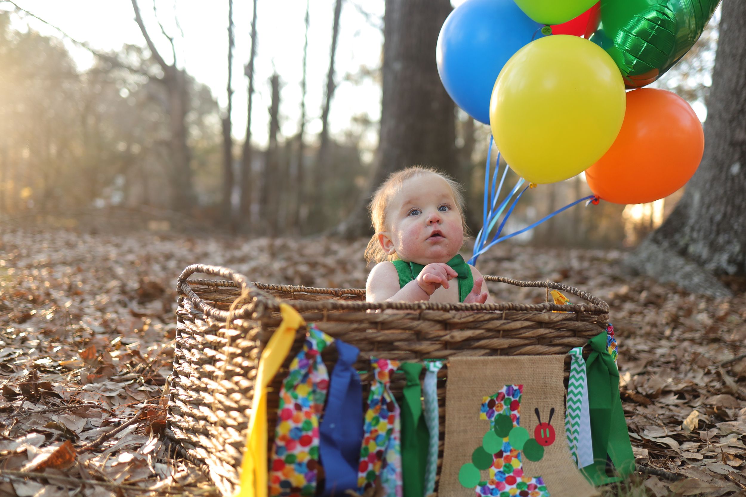 Colorful balloons bring brightness to a wooded autumn scene with fallen leaves and natural lighting.