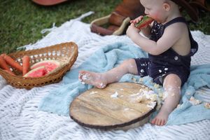 Someone enjoying fresh watermelon slices at a relaxing summer picnic on a blue blanket.
