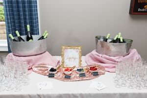 Champagne bar setup with ice buckets and glasses on a pink tablecloth.