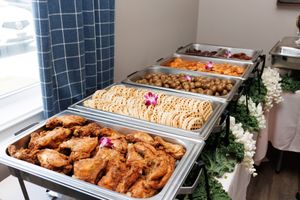 Catering setup with multiple chafing dishes filled with hot entrees and garnished with flowers.