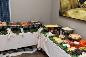 A catering table decorated with floral arrangements showcasing various food platters and appetizers.