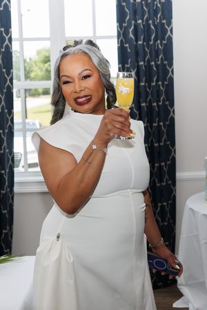 A celebratory toast with a champagne flute against blue patterned curtains.