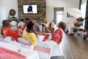 Wide view of party venue with stone accent wall and guests seated at decorated tables.