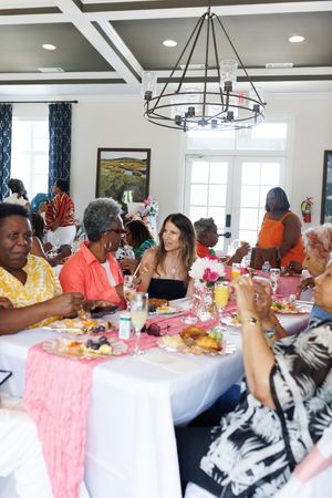 Diners enjoying a social gathering in a bright room with coffered ceilings and modern decor.