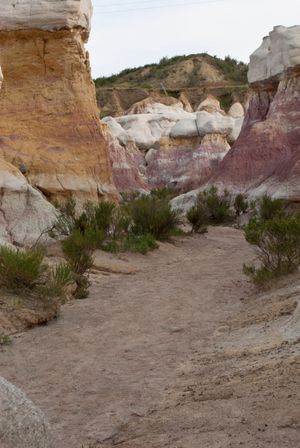 Panoramic view of colorful rock formations and sandy path winding through Paint Mines Interpretive Park in Colorado.