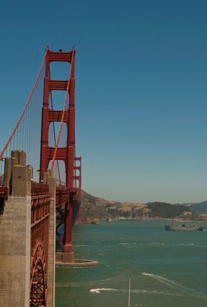Iconic red Golden Gate Bridge spans San Francisco Bay on a clear sunny day with turquoise waters below.