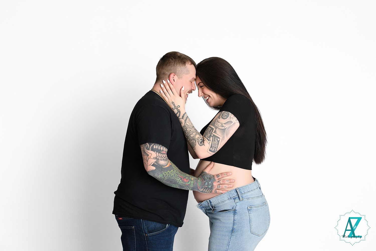 Couple in casual attire embracing against white background as they share an intimate moment.