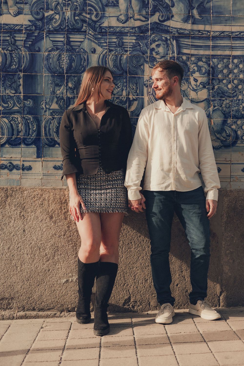 Couple posing against traditional Portuguese blue and white tile wall.