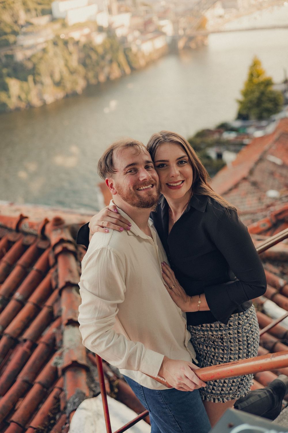 Romantic embrace against backdrop of terracotta rooftops and river.