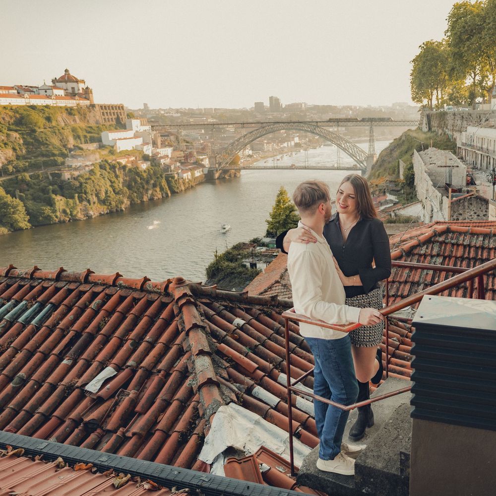 Couple standing on rooftop terrace overlooking scenic city view.