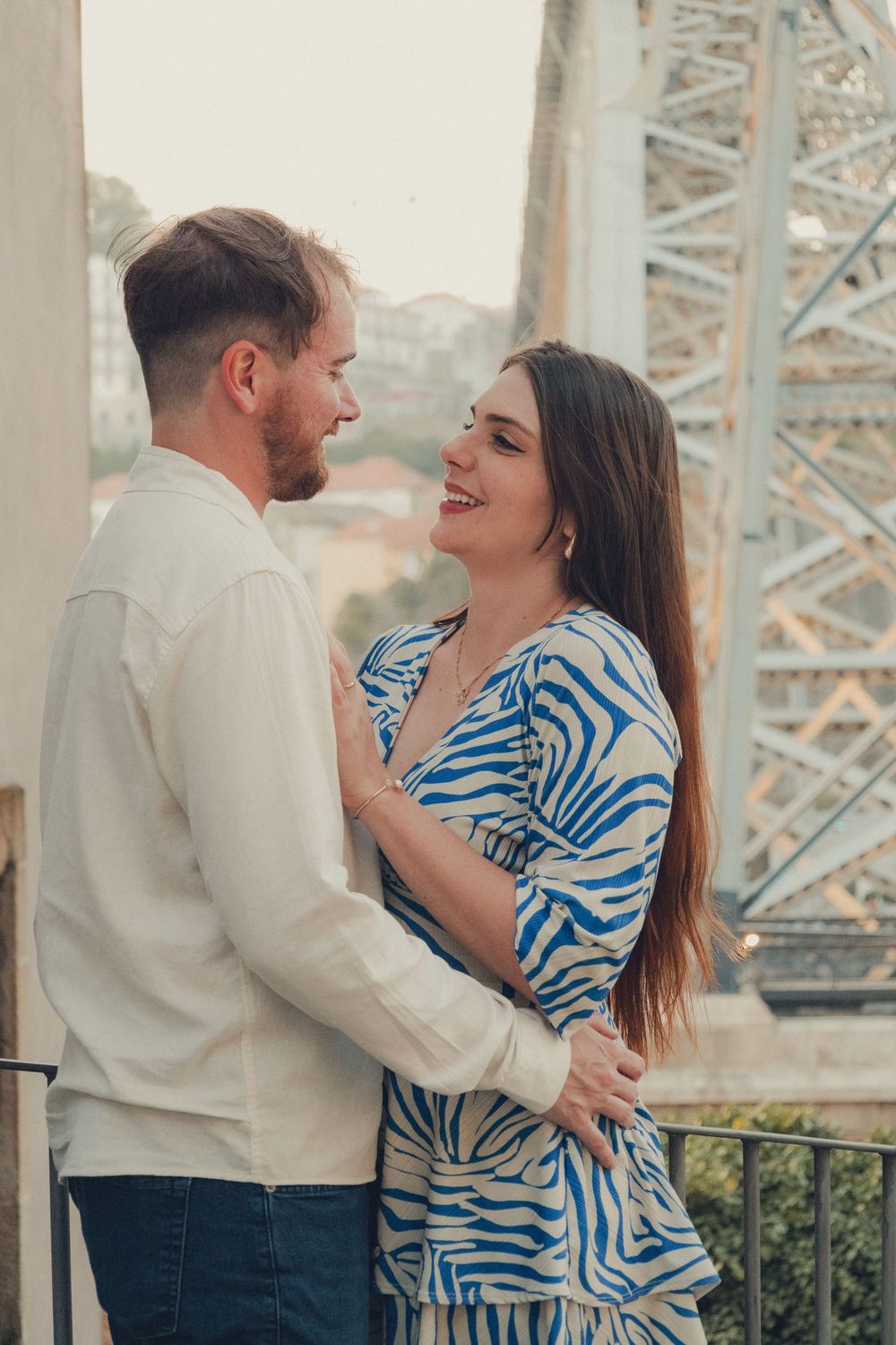 Dancing couple in coordinated outfits share intimate moments by a bridge structure.
